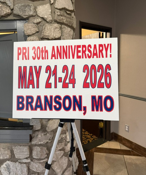 Sign announcing PRI 30th ANNIVERSARY! May 21–24, 2026, Branson, MO on a tripod in a stone lobby area.